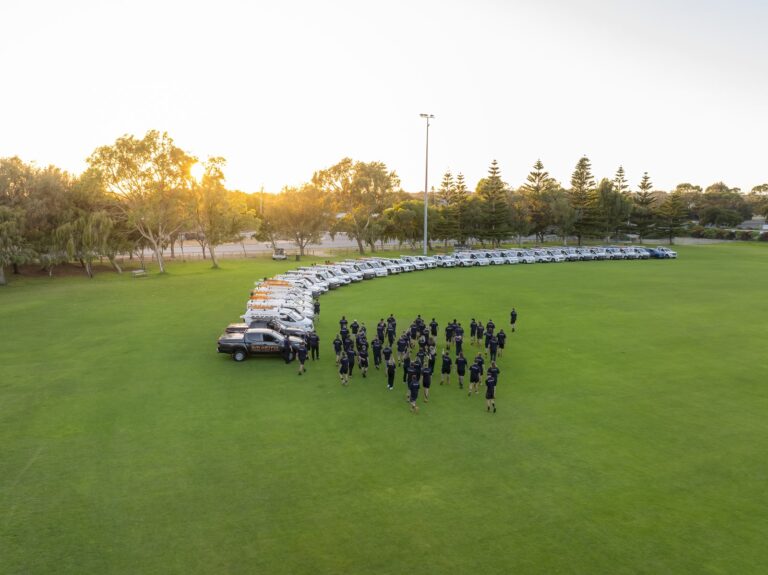 Smartfix team and fleet of branded utes lined up on a Perth oval